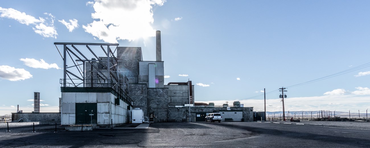 A color photo of a large reactor building under a blue sky with light clouds.