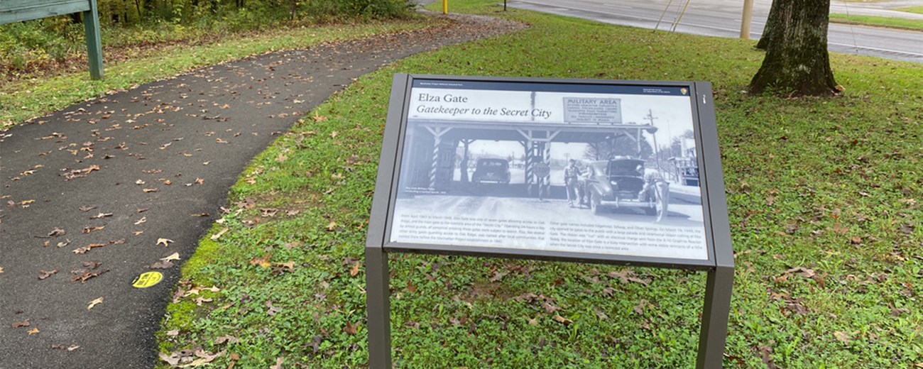 A wayside exhibit on a wooded path in a small city park.