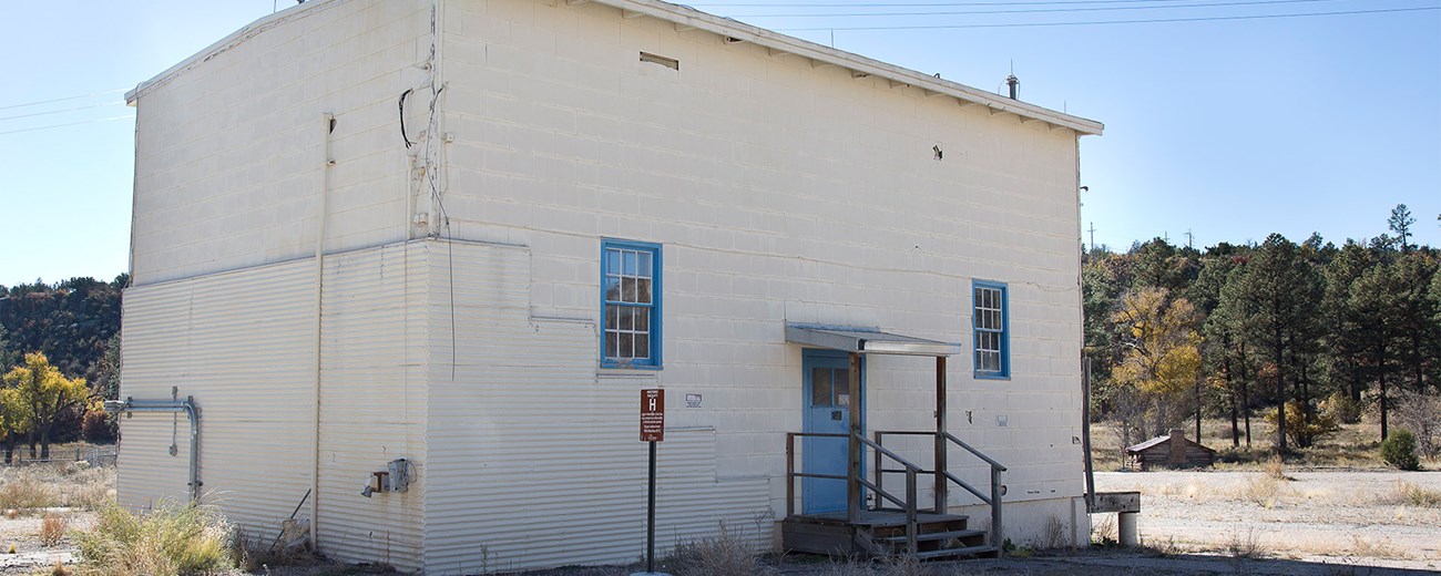 A square white brick building in a gravel lot.