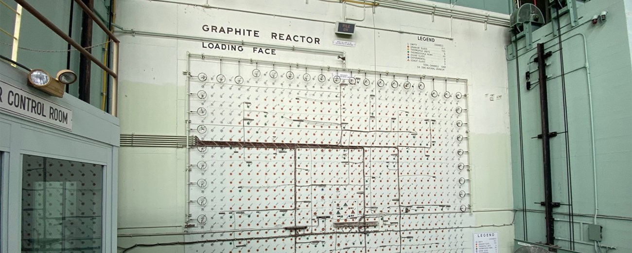 A color photo of a large green and off-white reactor face with the words Graphite Reactor Loading Face at the top of the face.