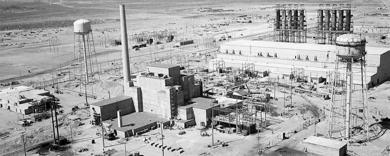 Black and white aerial photo of a large industrial complex on a flat desert plain.