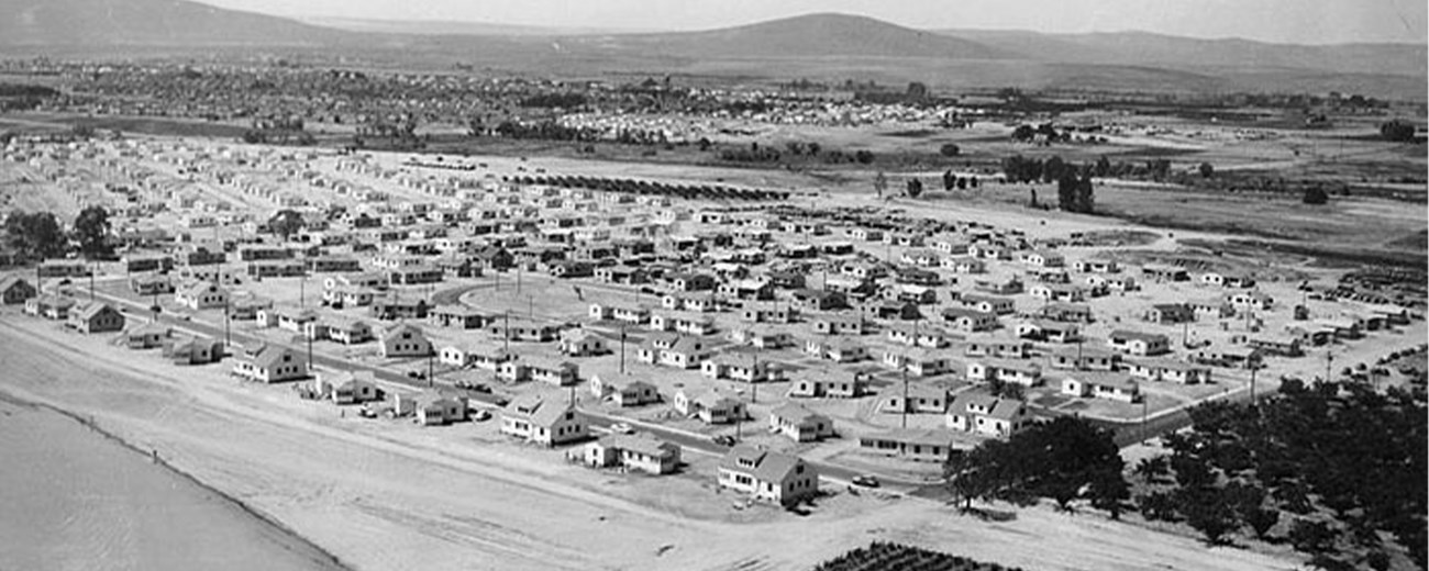 Aerial photo of a housing community on a flat desert with mountains in the background.