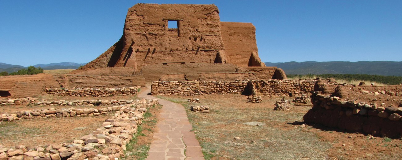 A red adobe brick building under a blue sky.