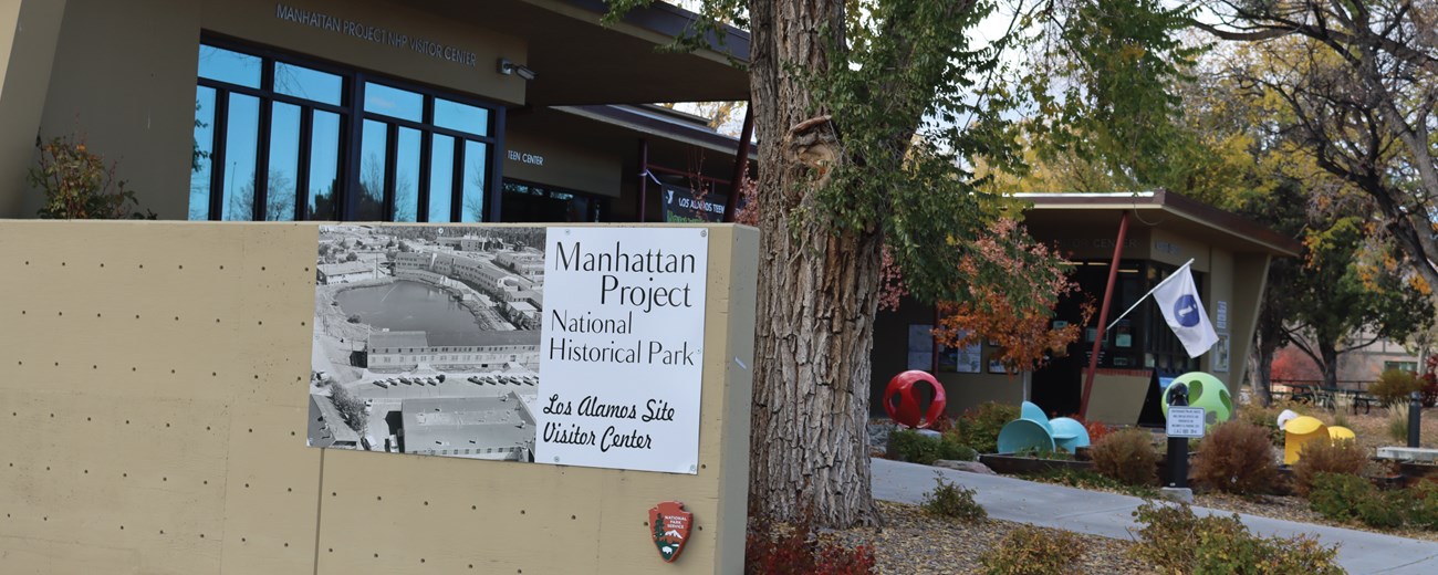 A tan building with a black and white sign that says, "Manhattan Project National Historical Site"