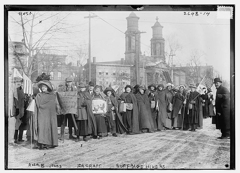 Women dressed in winter clothes march along a road holding picket signs