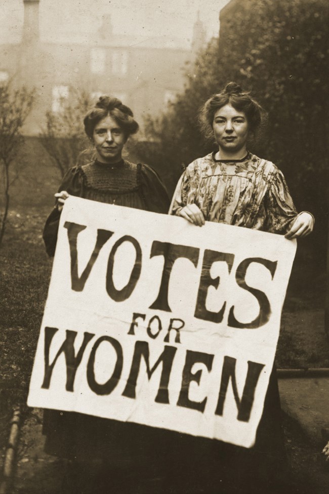 Two women holding a sign reading "Votes for Women"