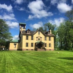 Large yellow house with trees and blue sky in background