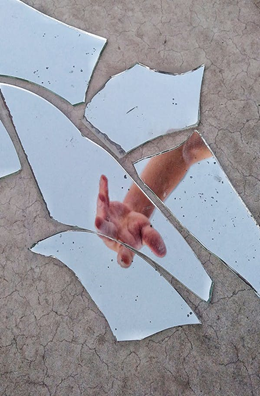 Mirror Fragments on Gray Surface With The Reflection Of A Person’s Arm