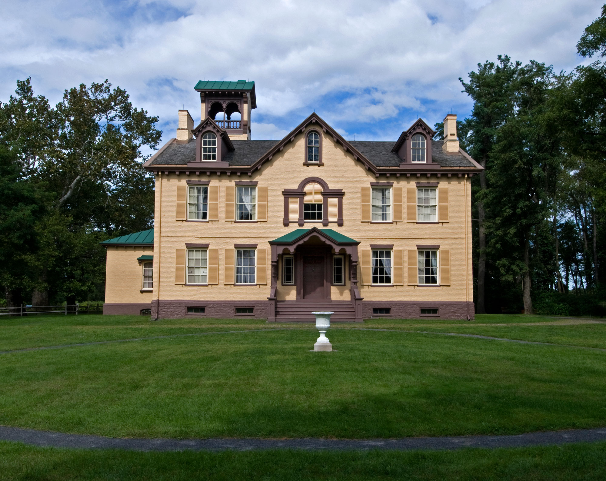 Large yellow house with trees and blue sky in background