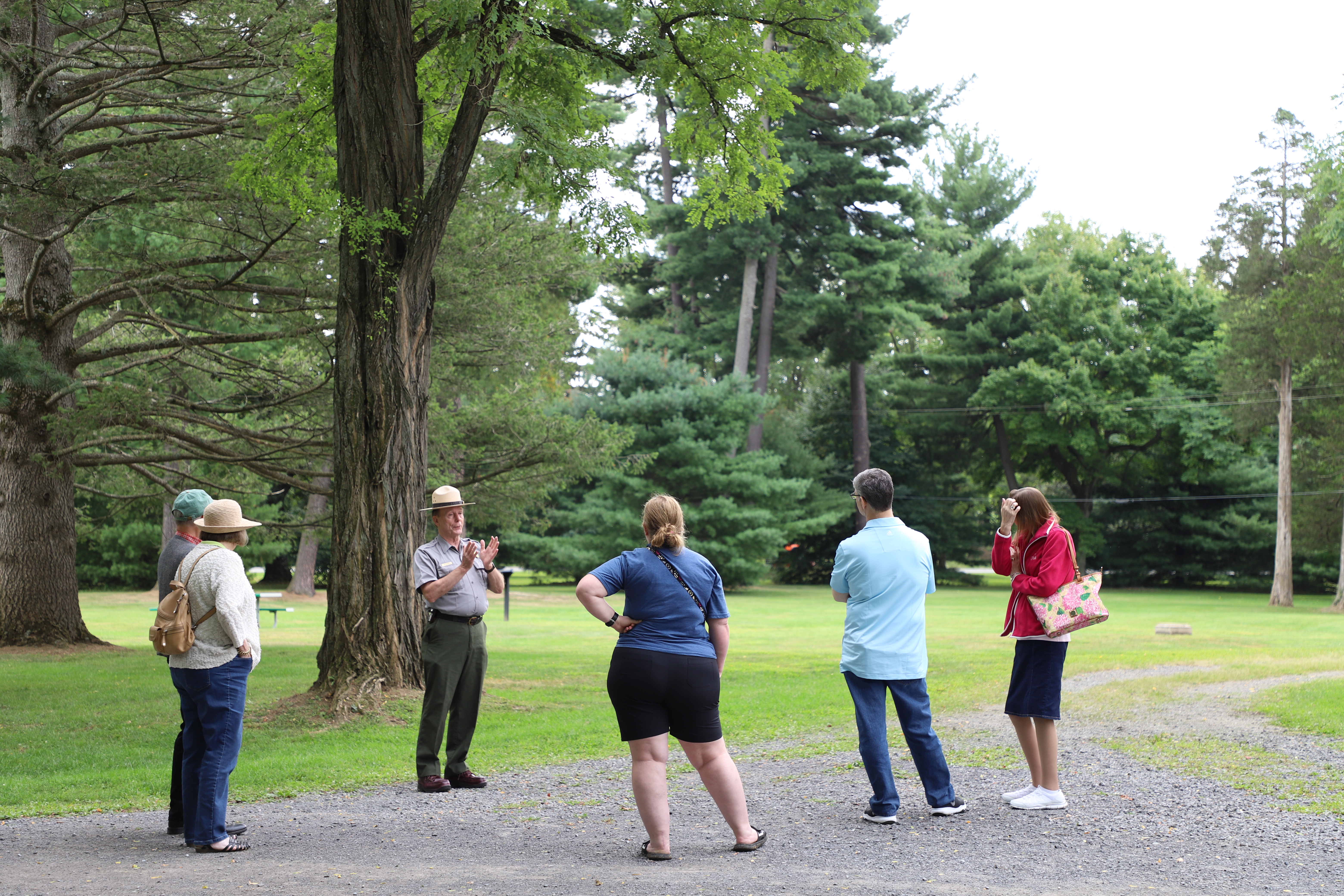 Photo of a park ranger speaking with visitors under a large tree