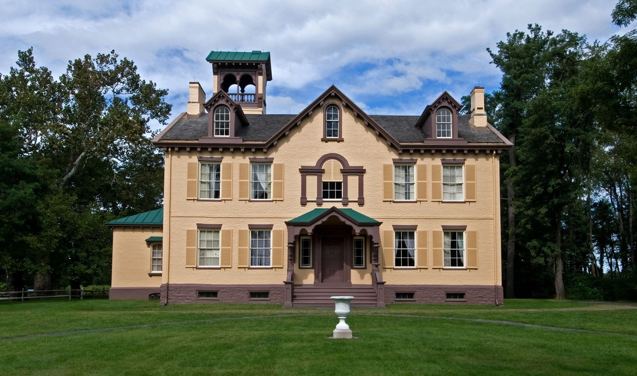 Gran casa amarilla con árboles y cielo azul
