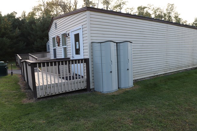 Two storage sheds housing art supplies next to a trailer