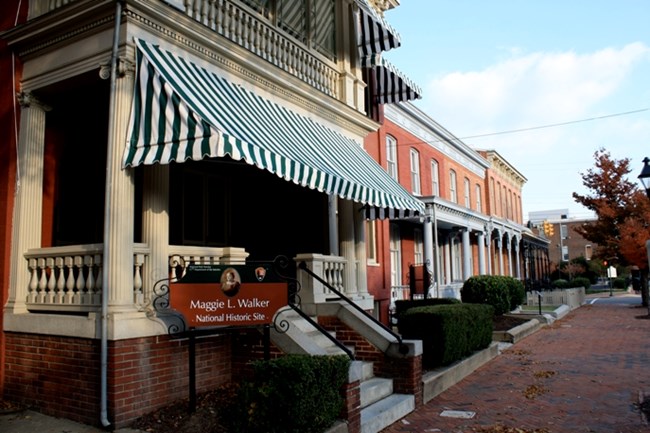 red brick row houses with green striped awning on house in foreground