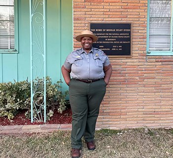 Ranger stands in front of Evers Home with dedication plaque just over her left shoulder
