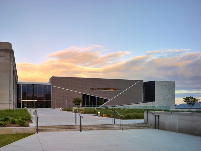 Large brick building with wide, expansive sidewalk that provides entry to museum.