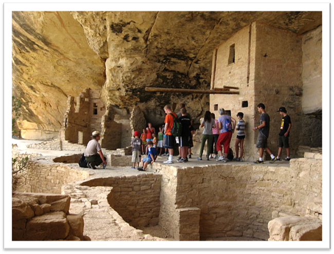 A group of visitors gather around ranger in balcony house.