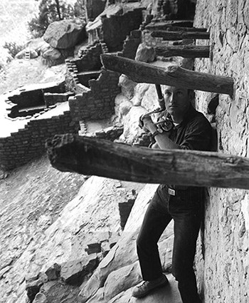 Man facing ancient wood beam with auger type instrument in hand.
