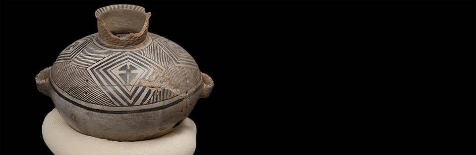 Large pottery jar with lid. Jar is white with painted black geometric designs.