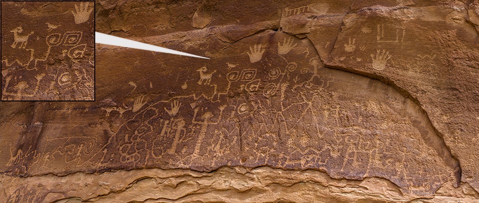 Petroglyphs chipped into a flat, sandstone panel. Includes handprints as well as animal and human figures.