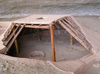 A wooden pole and mud structure constructed over a pit.