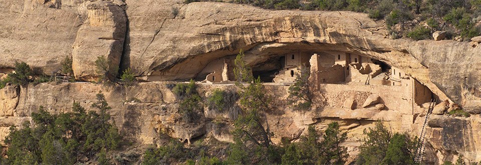 Sandstone cliff face with ancient, stone-masonry village within an alcove.