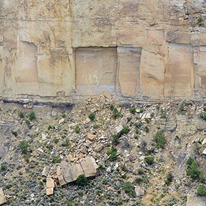 Sandstone cliff face with a square chunk of rock that has fallen off the cliff into the canyon below.