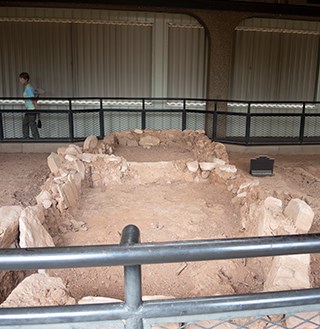 Archeological site showing the outline of single-stone masonry walled building.