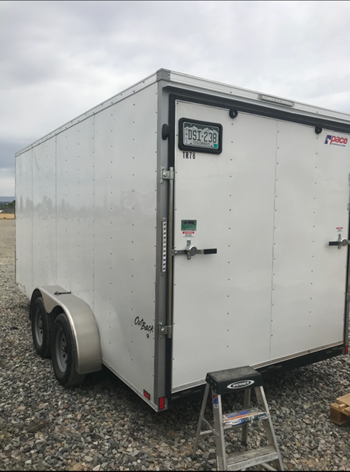 A white trailer with Colorado plates (DSI238) under a cloudy sky.