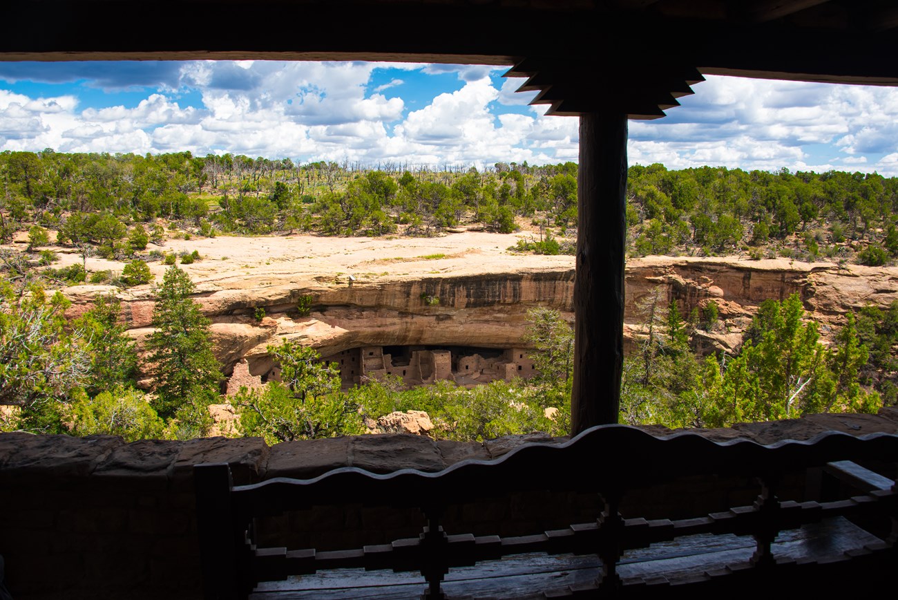 A view through a porch opening of an ancestral village set in a cliff alcove in a narrow canyon,
