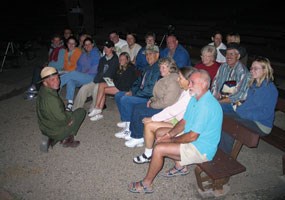 Ranger presenting an evening program to visitors in campground amphitheater. Ranger presenting an evening program to visitors in campground amphitheater.