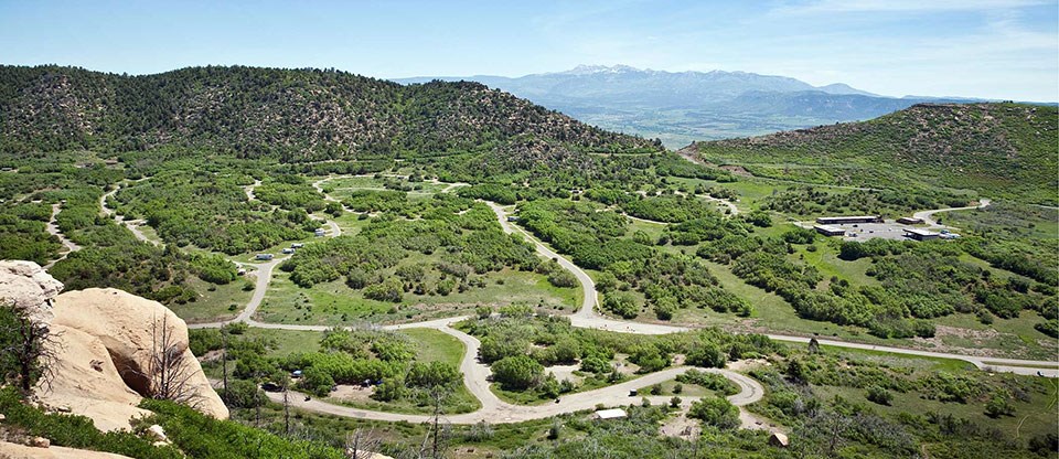 A high view of a wide canyon with roads to campsites and a magnificent view of the mountains in the background.