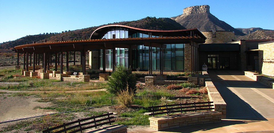Circular stone structure with tall glass windows and a flat mesa in the background.