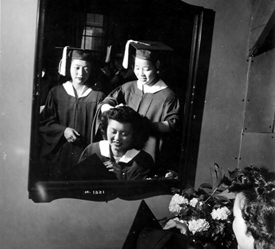 Women in graduation gowns in a mirror