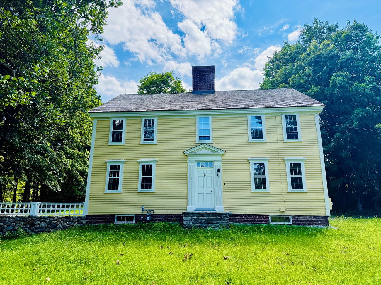 A yellow colonial era home with central chimney