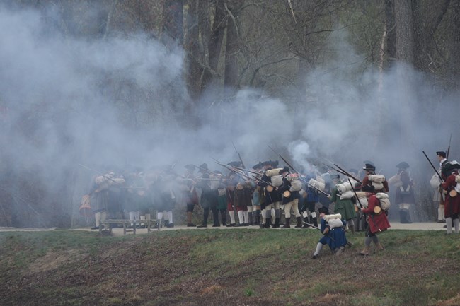 Militia soldiers open fire standing on a dirt road