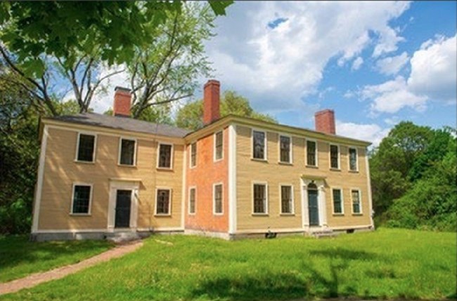 Yellow colonial house in green lawn