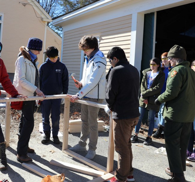 Students craft compost bin student with hammer nails wood together for compost bin