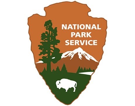 NPS arrowhead graphic showing Giant Sequoia tree, bison, snow peaked mountains, lake, and grassland.