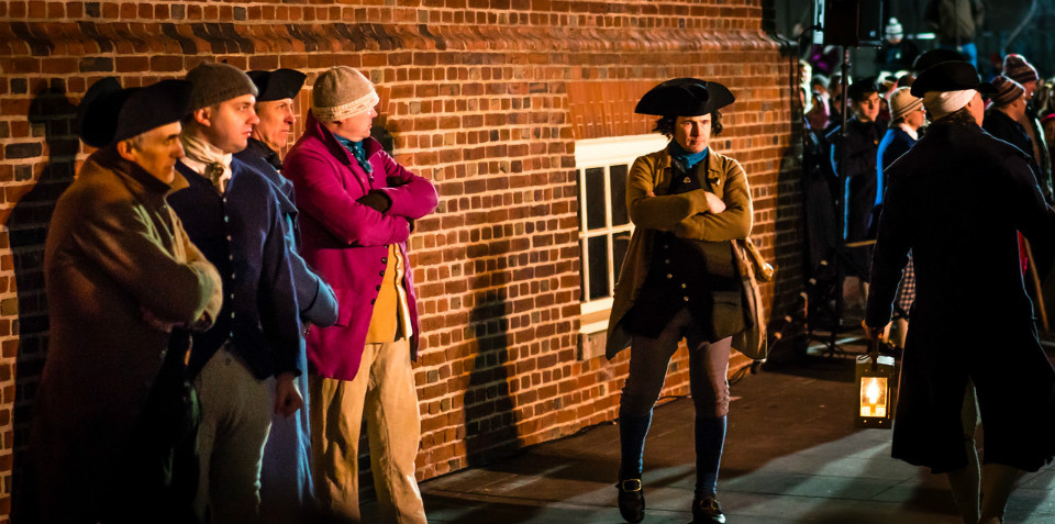 Patriots stand next to a brick building waiting for something to happen.