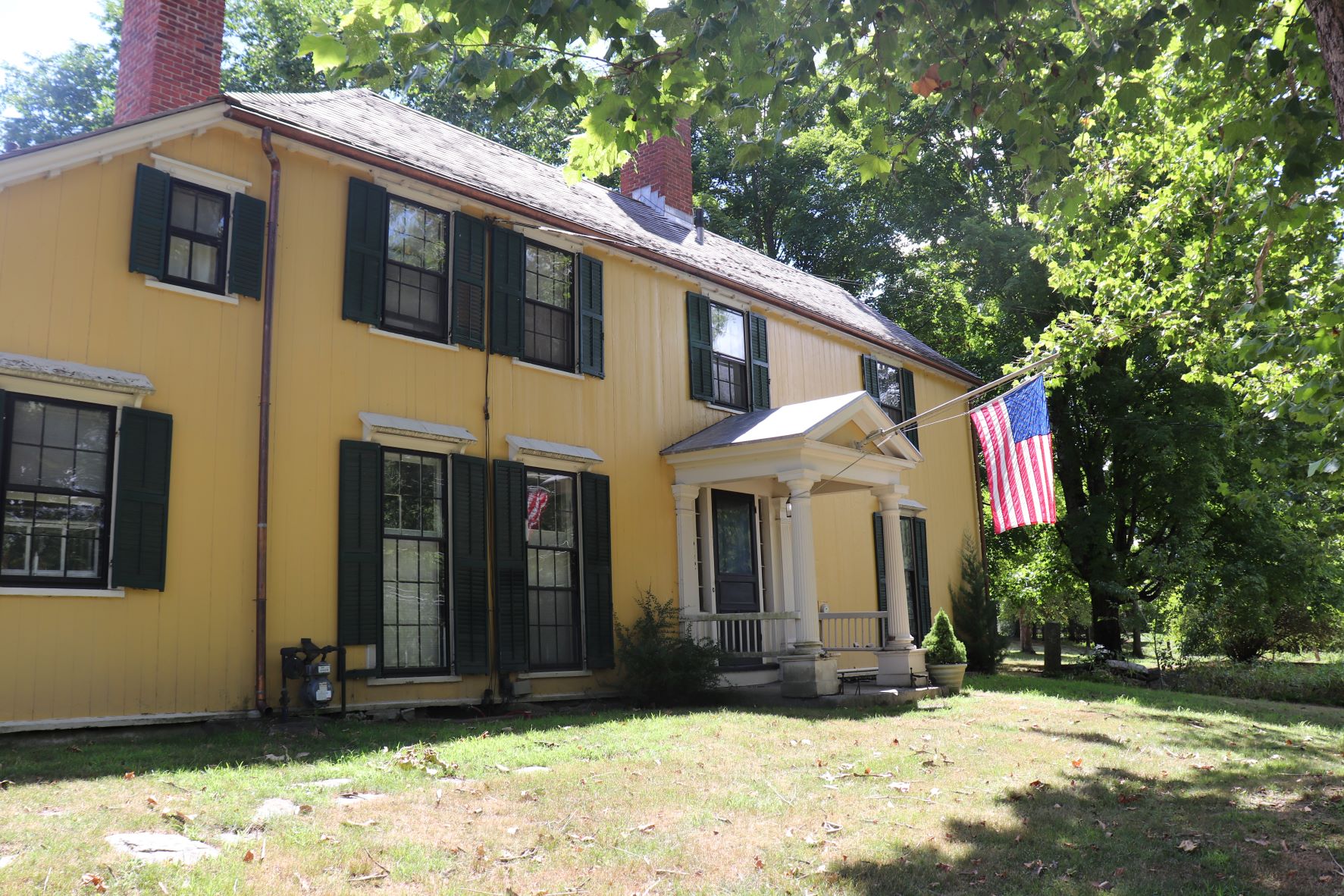 Large yellow two story house with American flag on porch