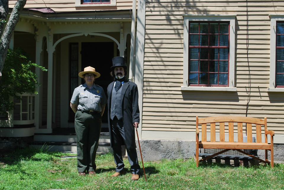 Female park ranger on left stands with a Nathaniel Hawthorne reenactor