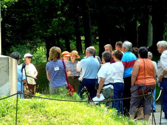 A park ranger talks to a group of people. A park ranger talks to a group of people.