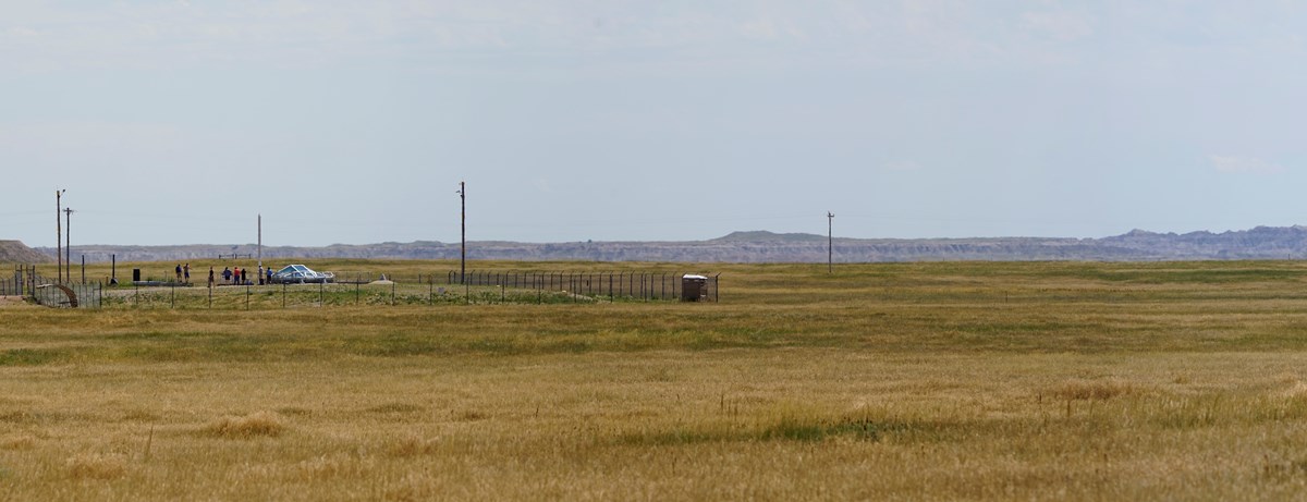 A fenced enclosure with concrete and metal features is surrounded by a prairie landscape A fenced enclosure with concrete and metal features is surrounded by a prairie landscape