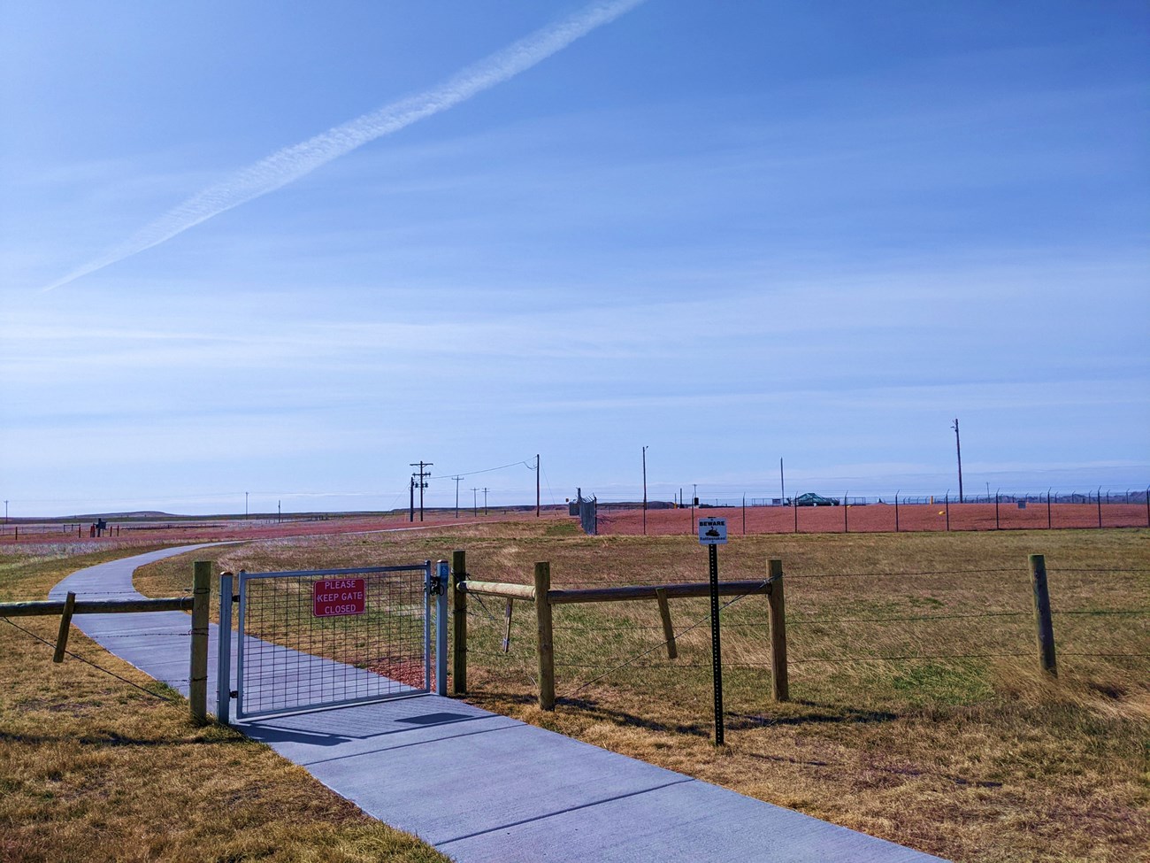 View of Delta 9 missile site looking south. Chainlink fence around gravel in the middle of a field.