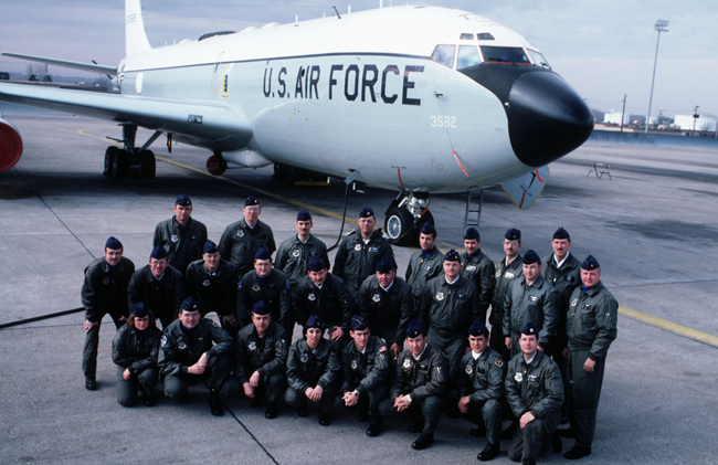 Group of Air Force officers in uniform posing in front of a large white airplane with Air Force markings on it