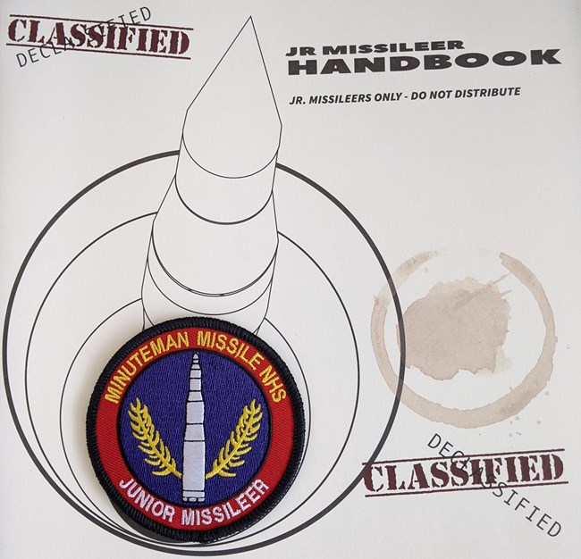 Cover of a booklet featuring a missile in a silo and a junior ranger patch