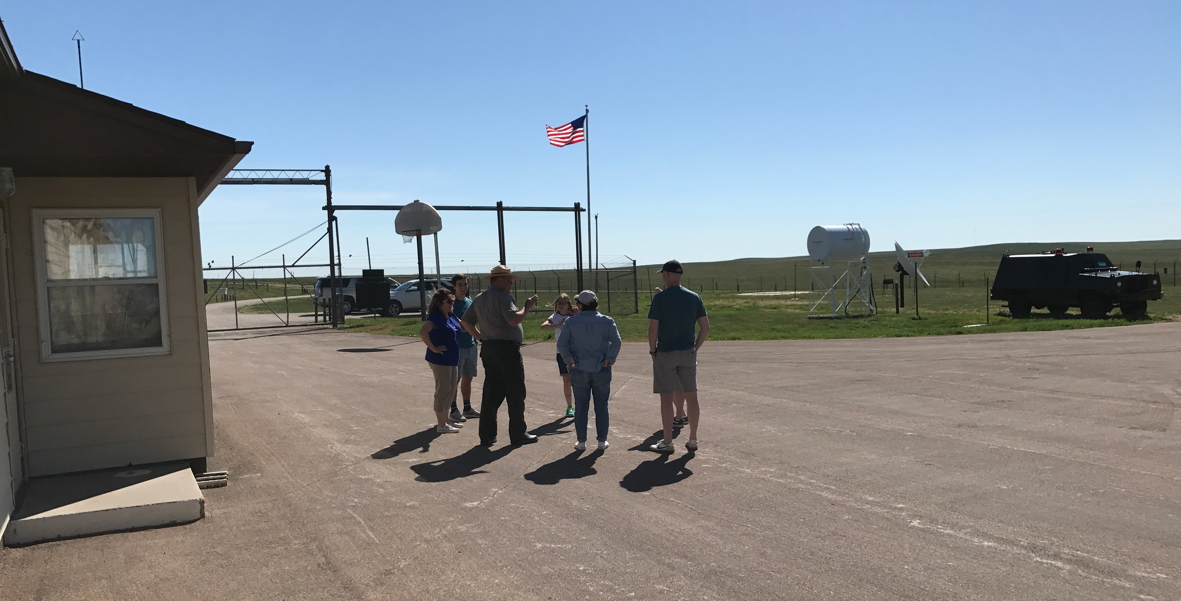 A park ranger talks to a group of people inside a fenced compound A park ranger talks to a group of people inside a fenced compound