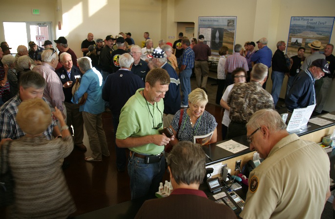 A crowd of visitors inside a building; staff work behind a desk