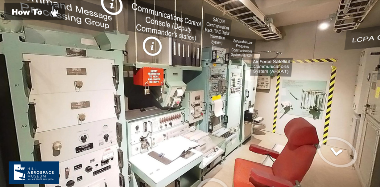 Inside of an underground bunker with two red chairs and green computer equipment.
