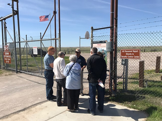 A group stands at an open fence gate